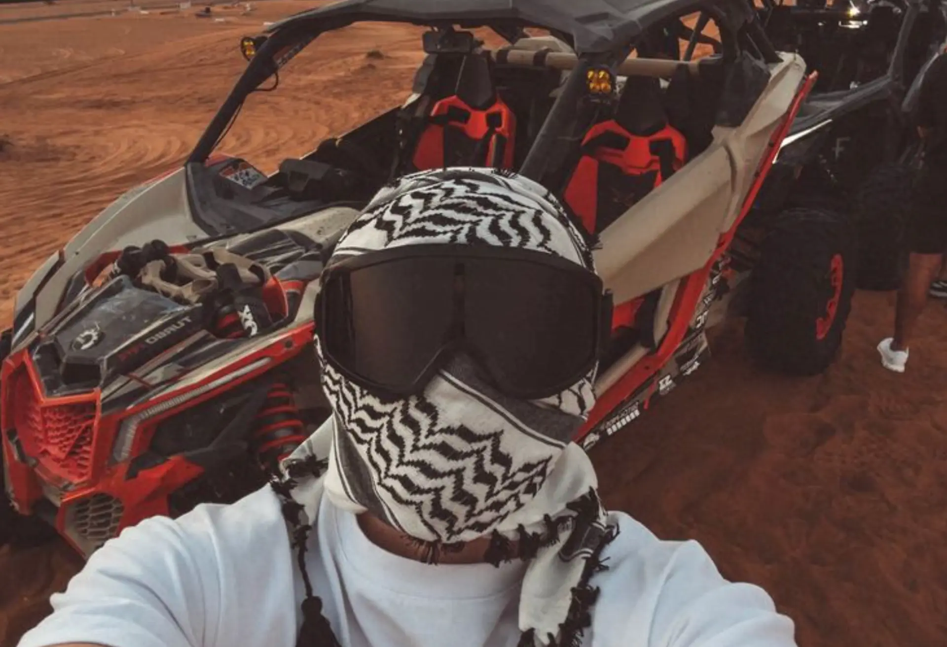 Rider in goggles and scarf in front of a desert buggy